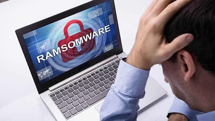 Man upset in front of laptop with Ransomware