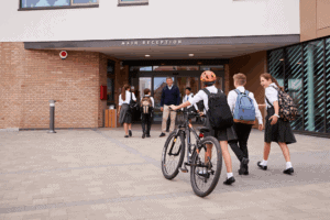 Students entering school building in uniforms and backpacks.