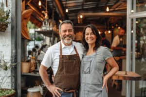 Smiling café owners in aprons, standing together happily.