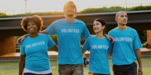 Group of volunteers in blue t-shirts smiling outside.