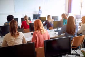 Students in classroom with computers and teacher.