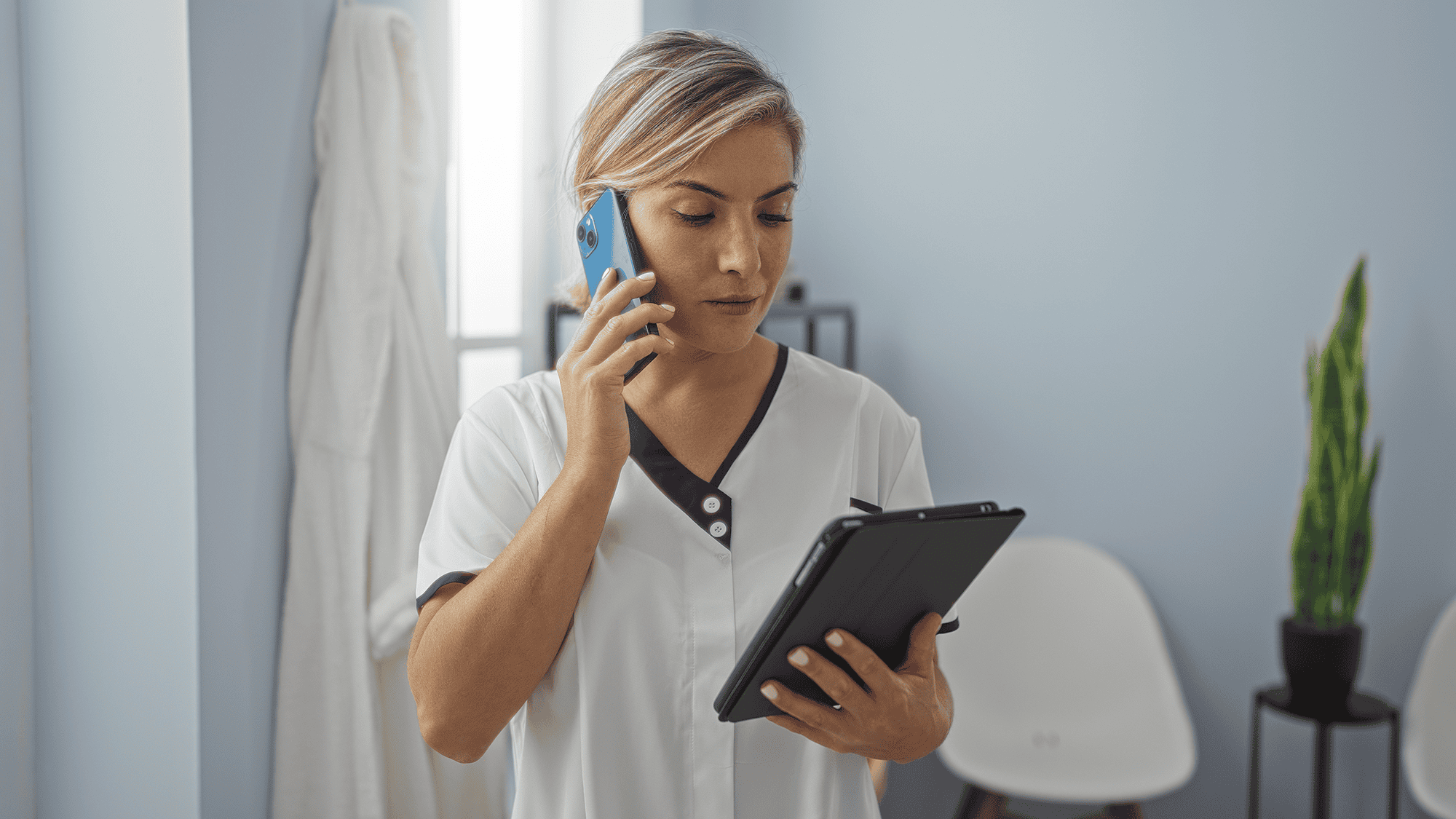 Healthcare professional on phone and tablet.
