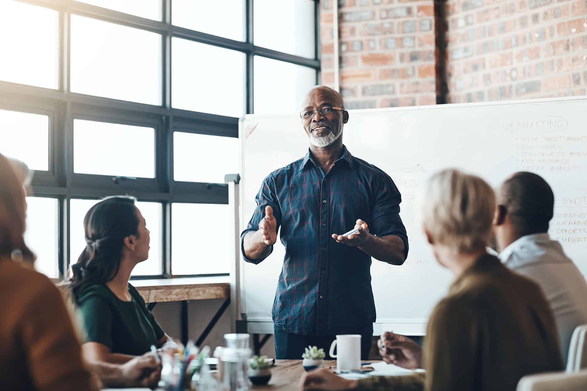 Man presenting to colleagues in a meeting room.